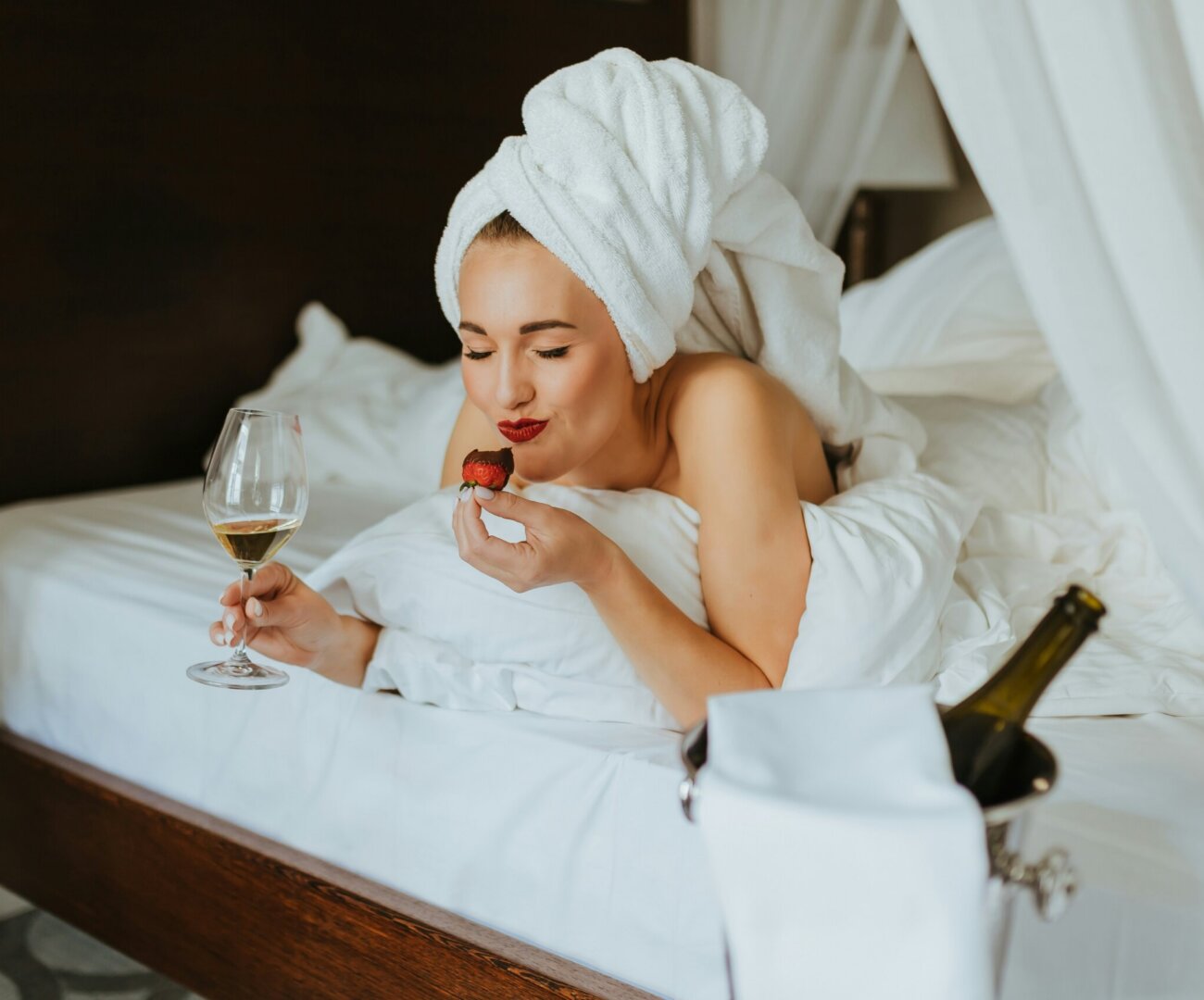 Frau mit Wein und Erdbeere im Bett