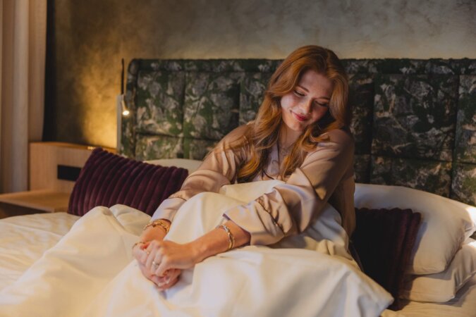 Gast entspannt im Bett eines Designzimmers im Hotel nōa Schladming.
